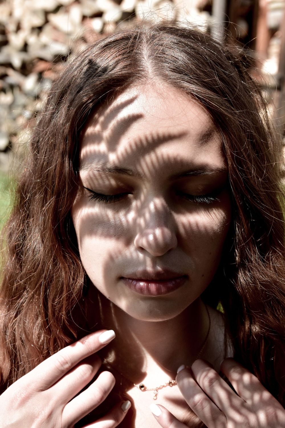 Gesicht einer Frau mit Blattschatten im Sonnenlicht (Symbolbild)